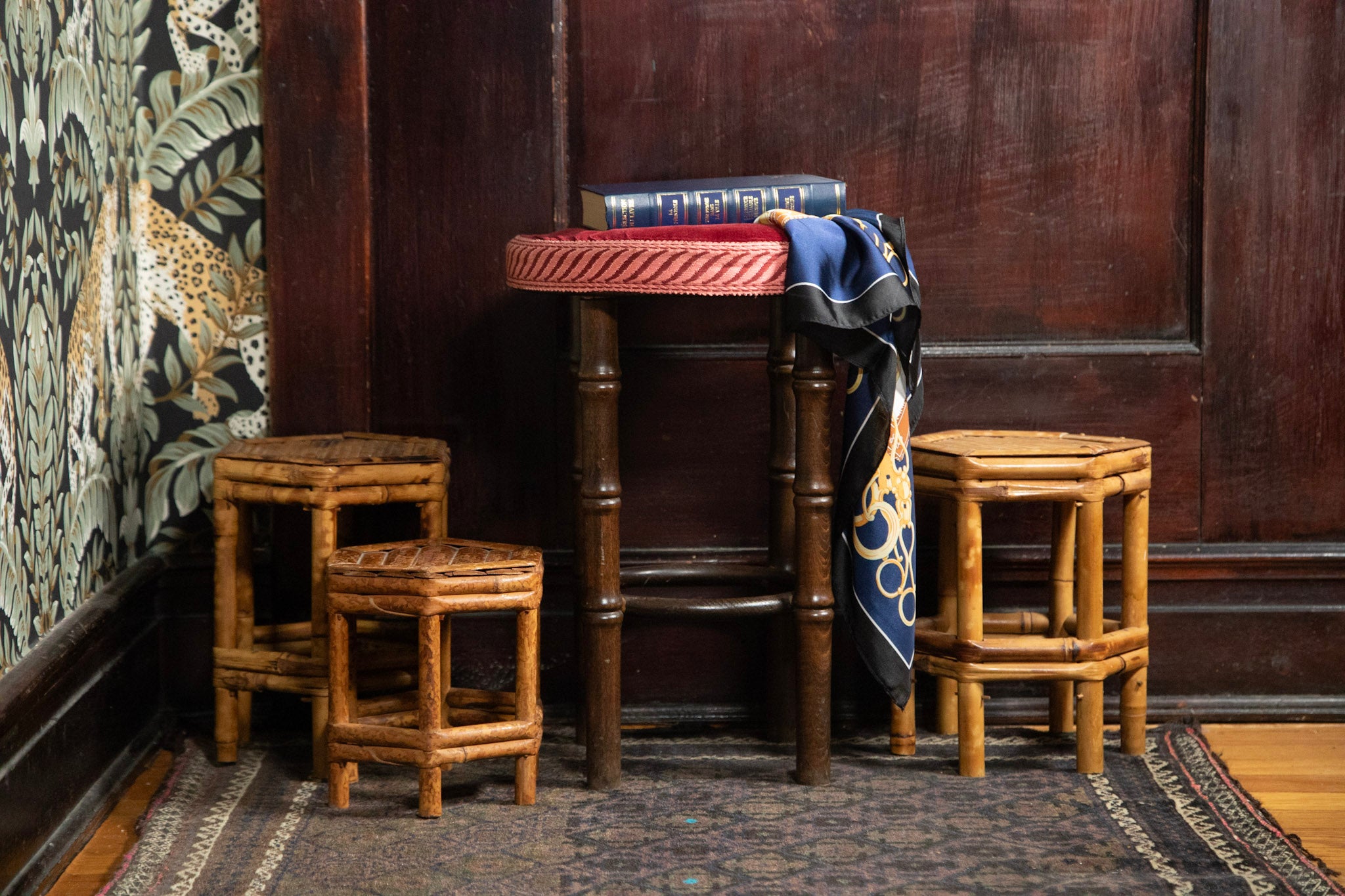 Set of wooden stools in a room with patterned wallpaper and a rug.