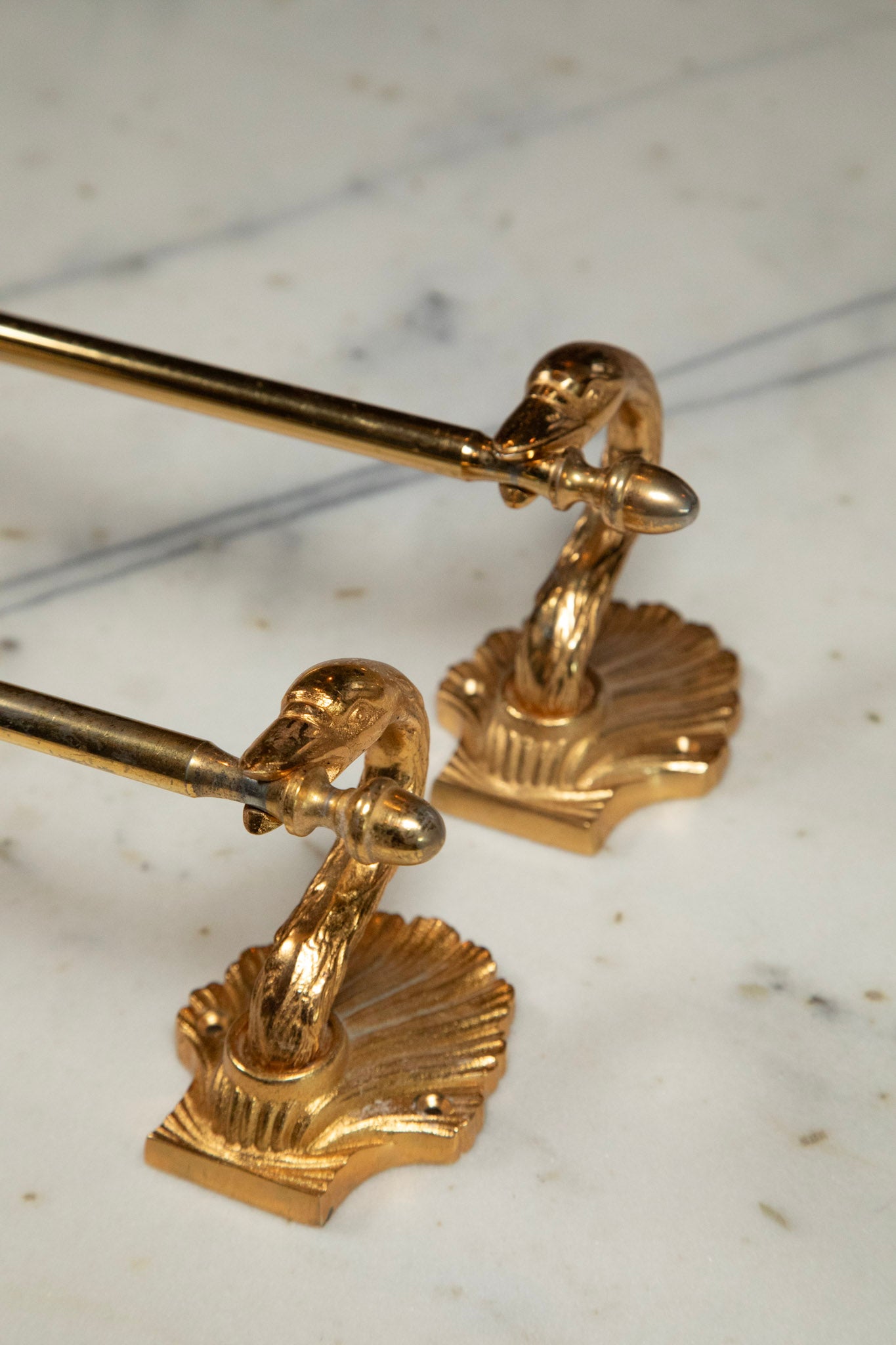 Gold towel holders with shell design on a marble surface