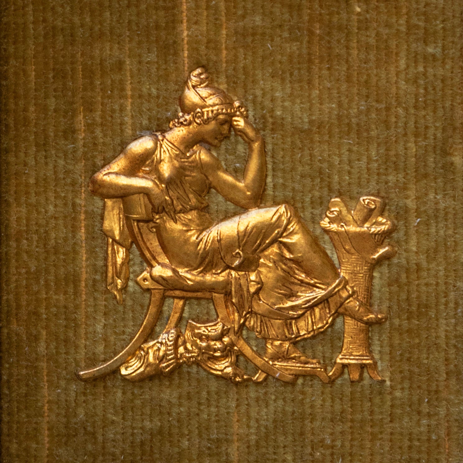 Gold embossed design of a classical figure on a textured brown background