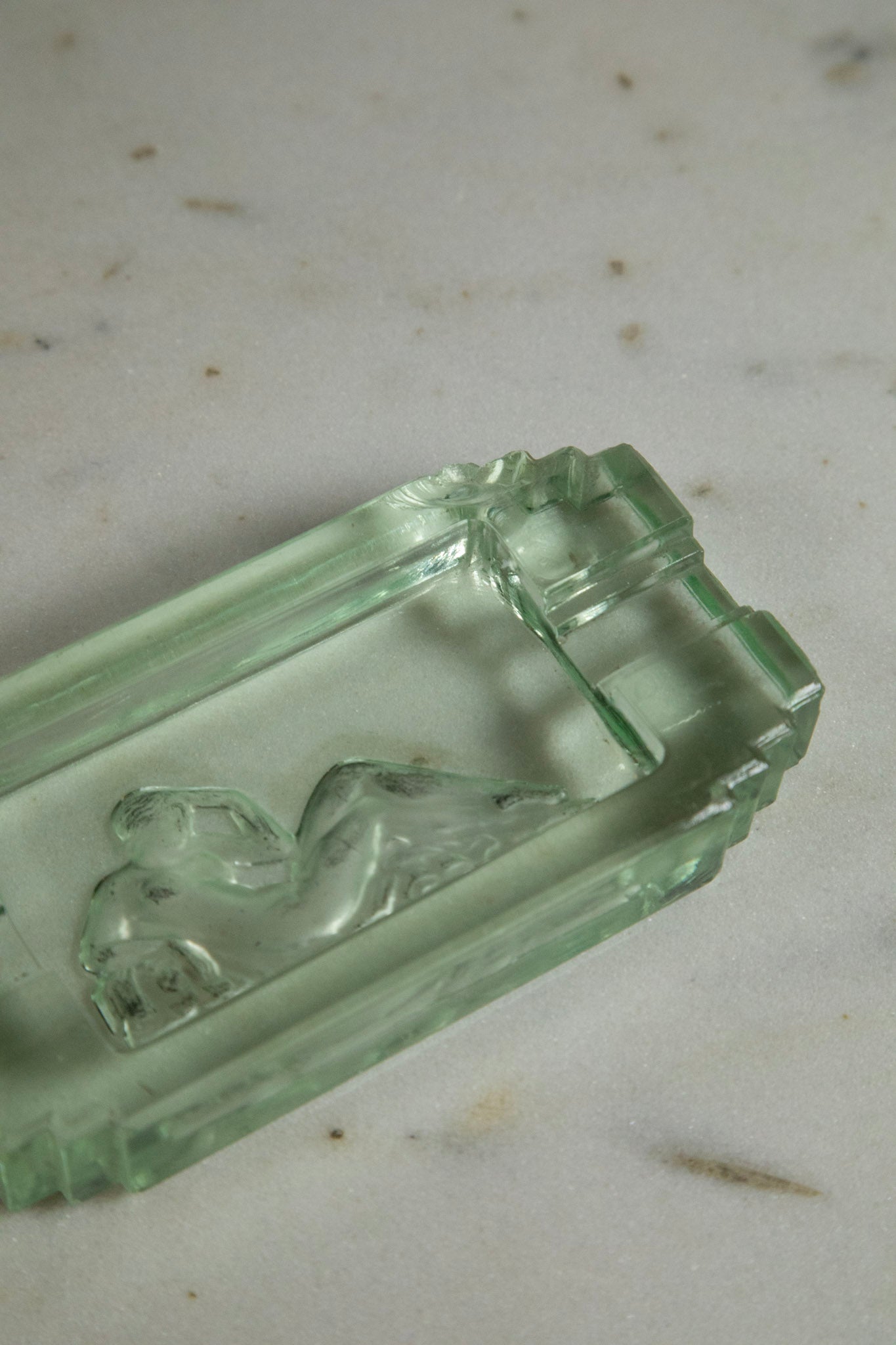 Clear glass dish with embossed design on a light gray background