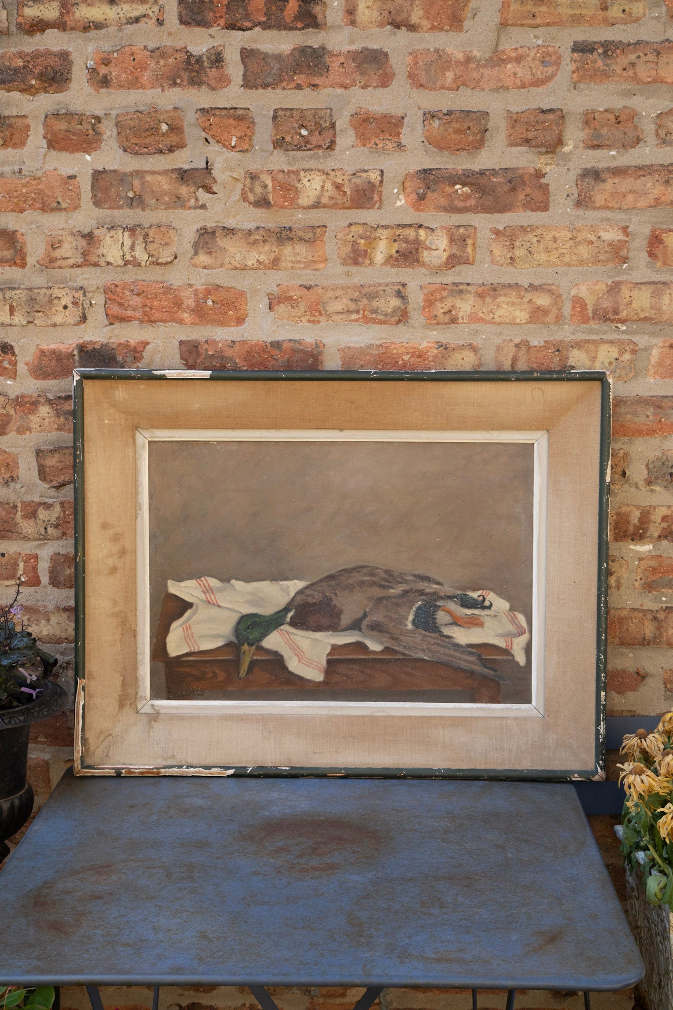 Framed painting of a duck on a brick wall