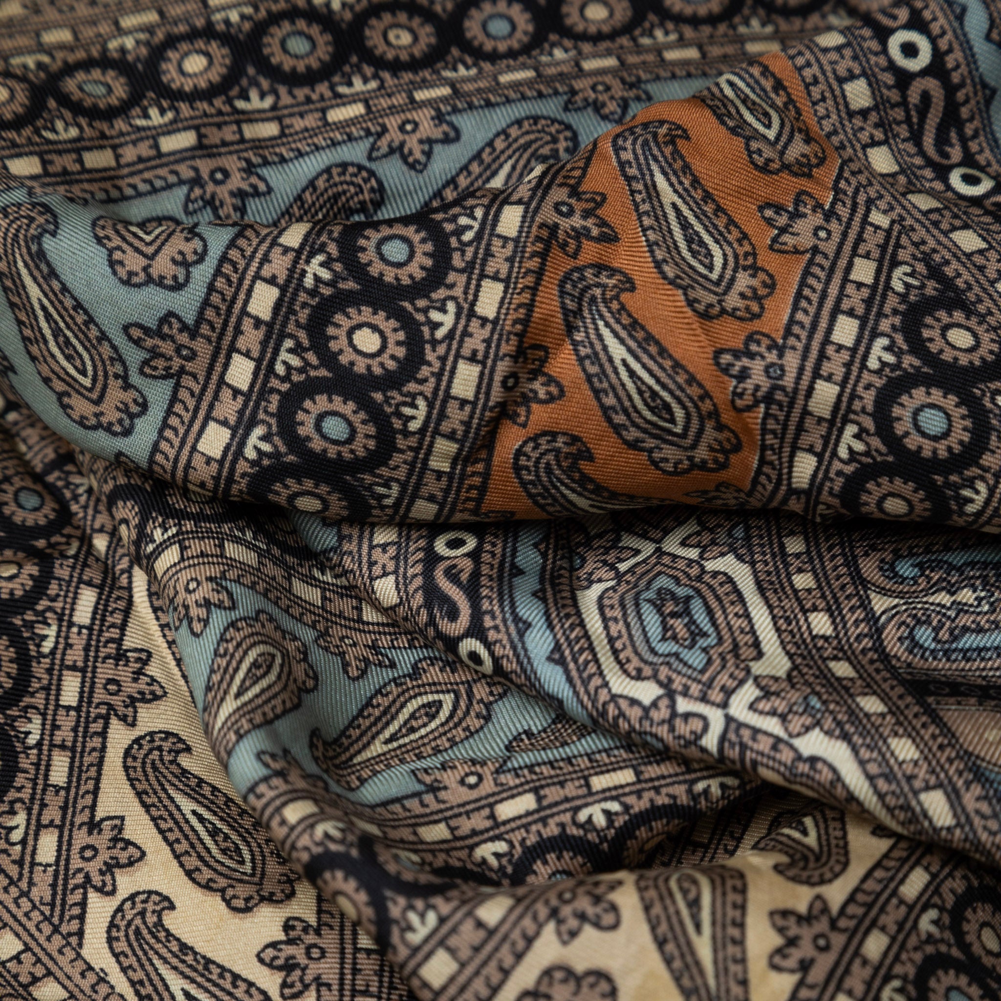 Close-up of patterned fabric with intricate designs in brown, blue, and beige.