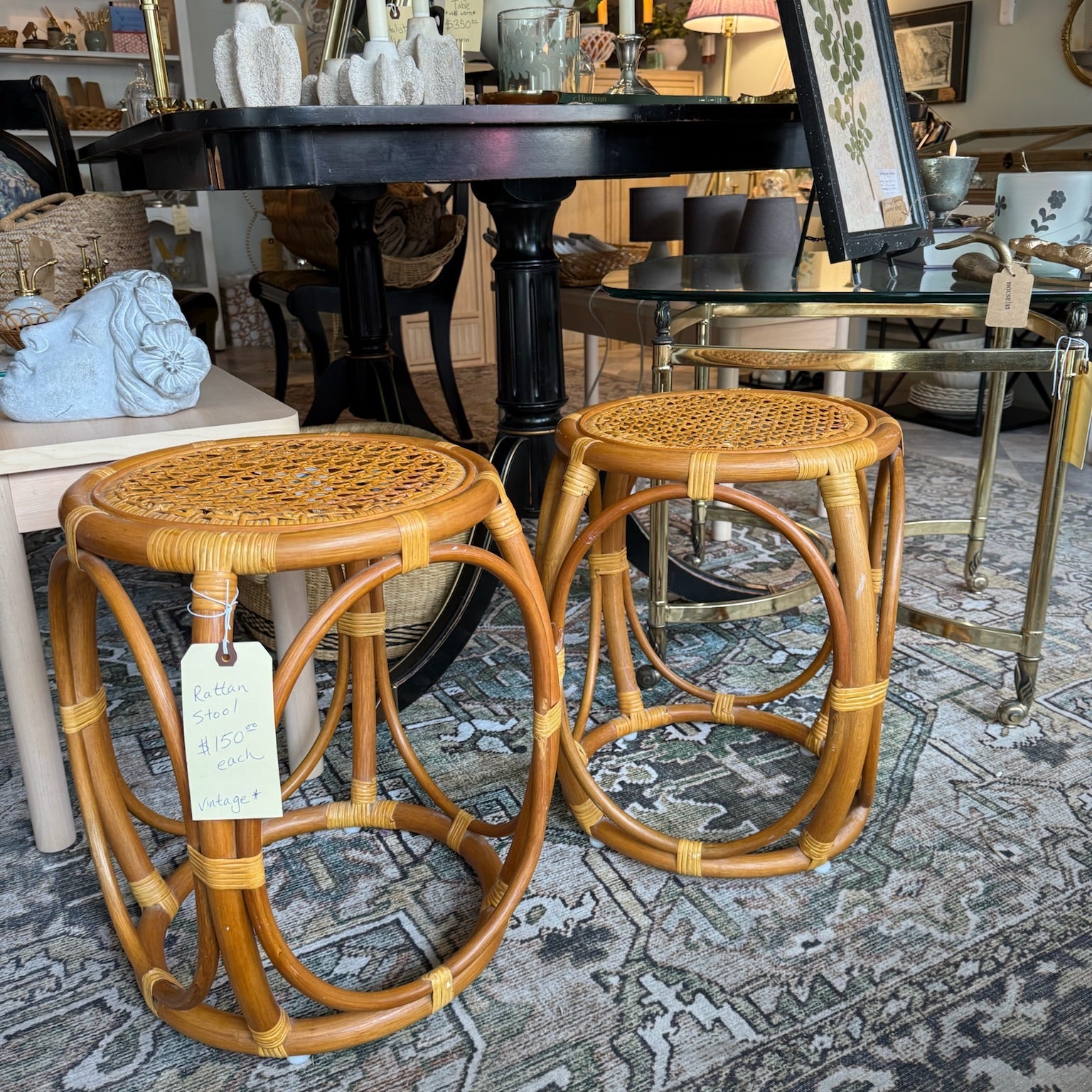 Two wicker stools with price tags in a store setting.