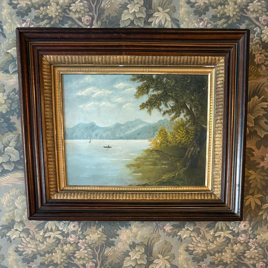 Framed landscape painting above decorative dogs and vases on a floral wallpapered wall.