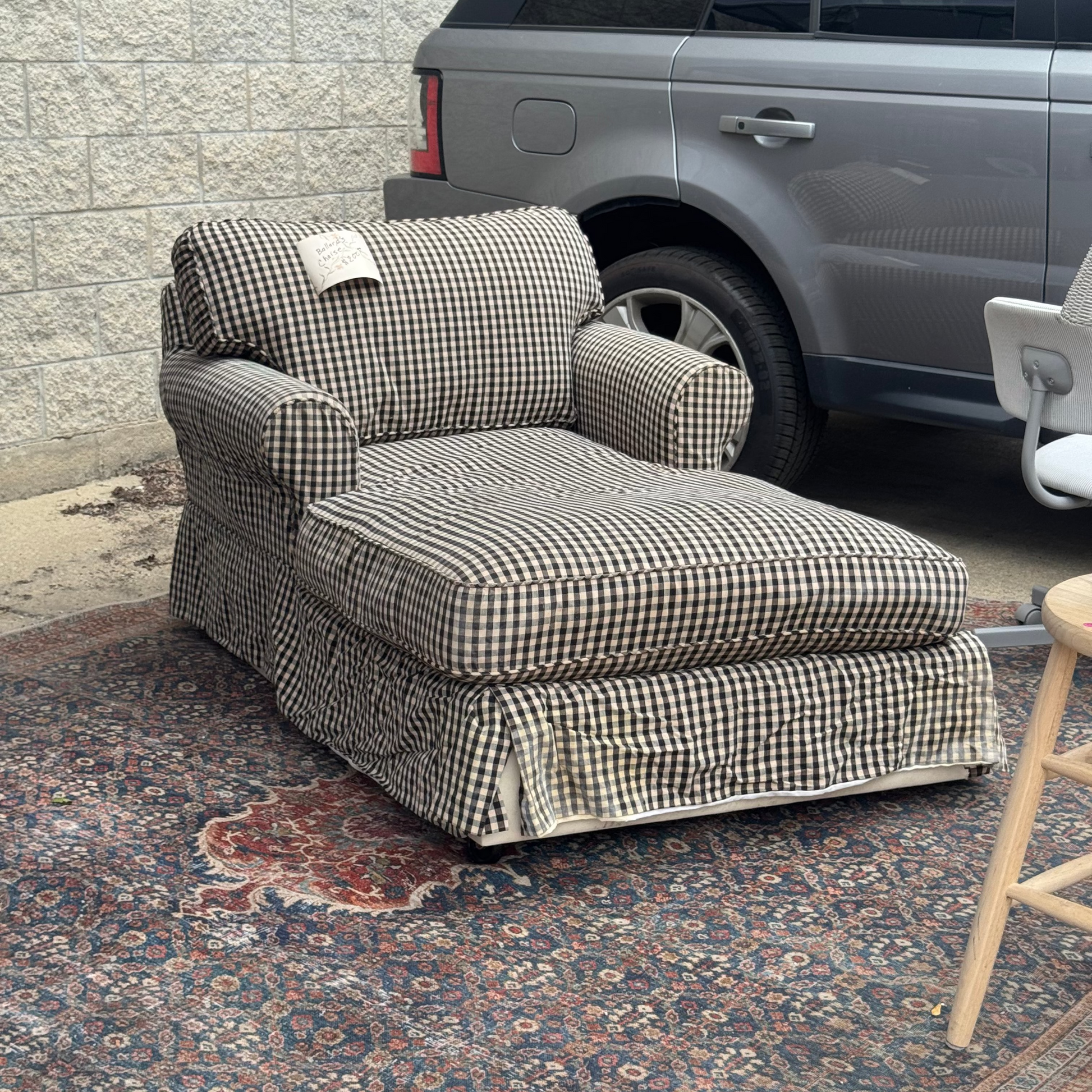A slipcovered chaise lounge chair with a black and white gingham check pattern.