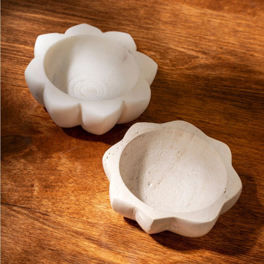 Two white stone flower-shaped objects on a wooden surface