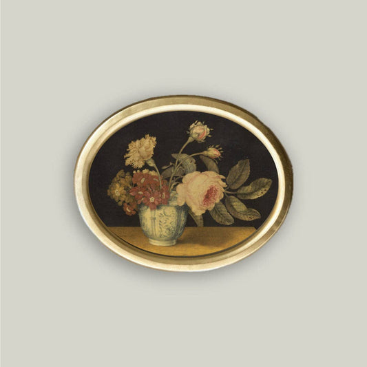 Decorative wall art with a floral arrangement in a vase on a dark background, framed by a gold border.