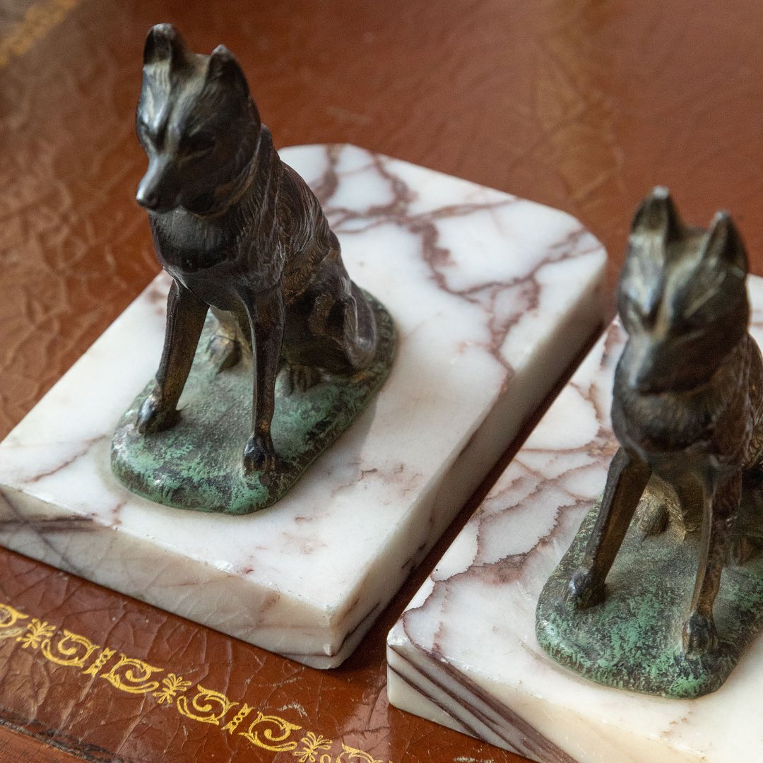 Bronze german shepard statues on marble bases with a leather-bound book in the background
