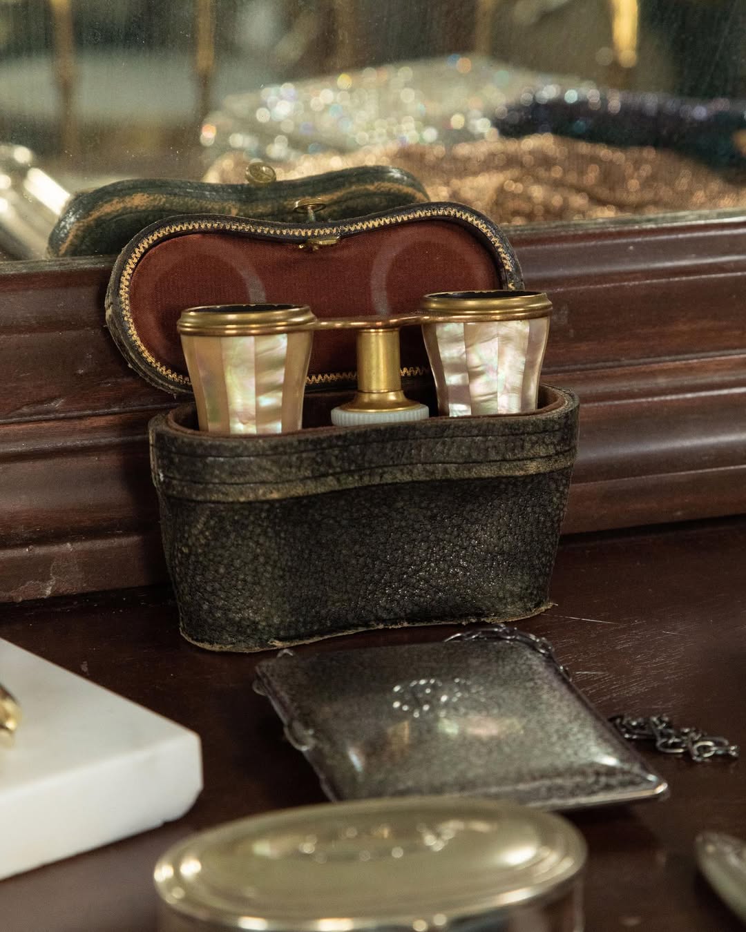 Set of vintage mother of peal opera glasses in a leather case on a wooden surface